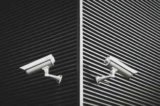 Two security cameras mounted on the walls of a building