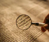magnifiying glass over old scripture